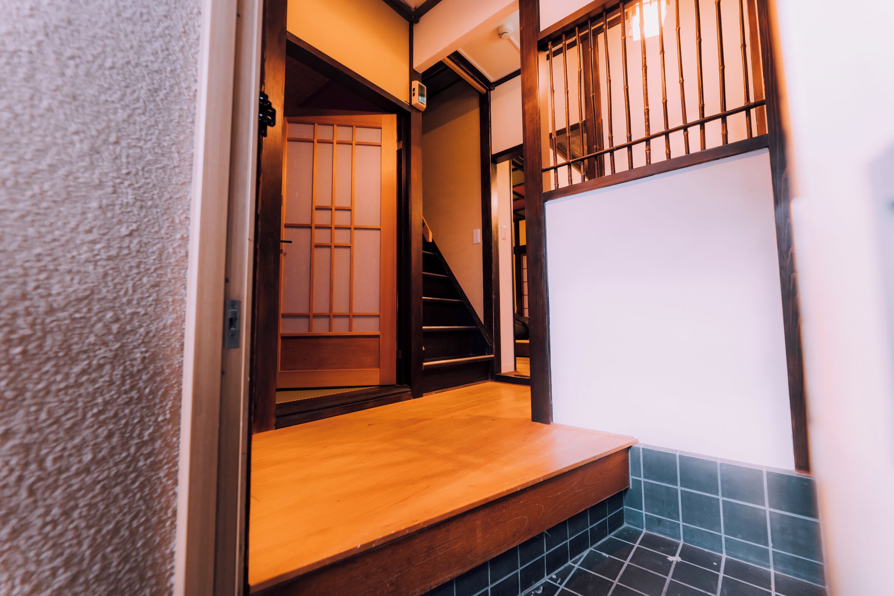 A wooden staircase leading to a room with a sliding door and a tiled floor.