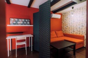 A room with a red wall, a white chair, a black table, and an orange sofa. - Ninja 4BR Tennoji 5 Min (Osaka)