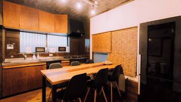 A modern kitchen with wooden cabinets, a central island, and a dining area with chairs.