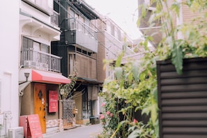 Una calle estrecha con edificios tradicionales, una puerta de madera y un toldo rojo.