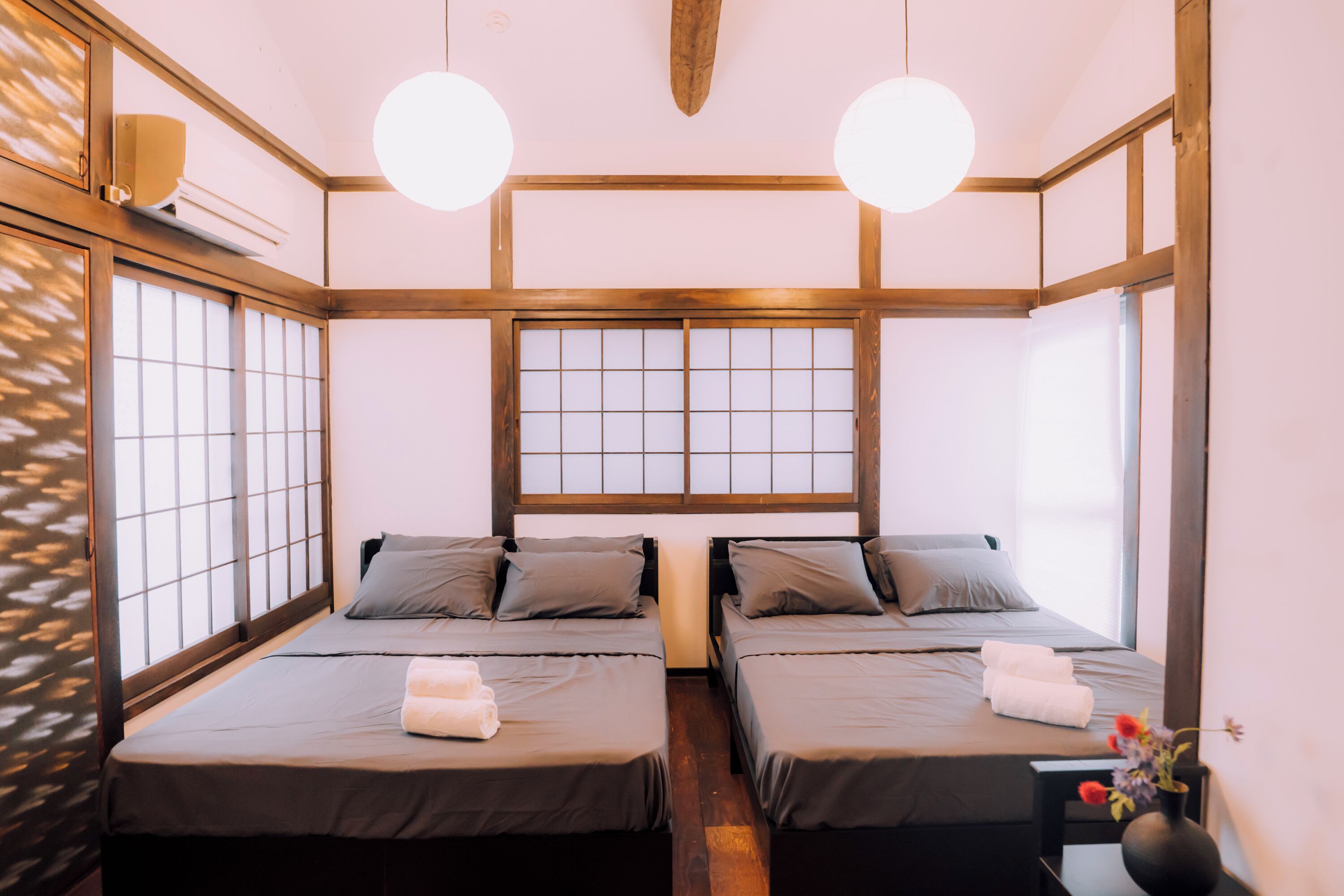 A traditional Japanese-style room with two beds, a shoji screen, and a wooden ceiling structure.