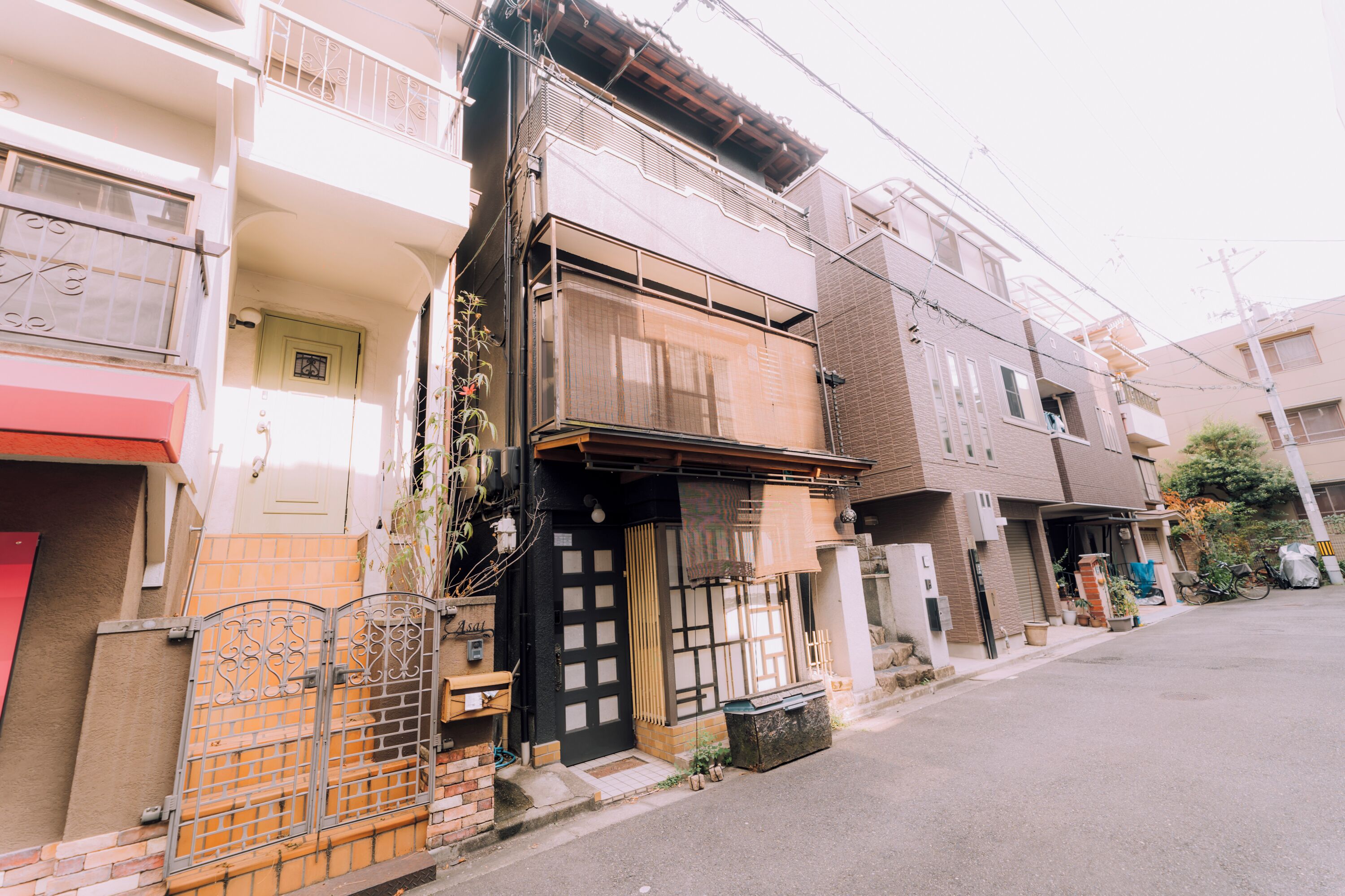 A residential street with traditional Japanese architecture, including wooden doors and sliding shutters.