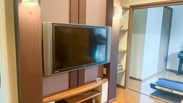 A flat-screen TV mounted on a wooden wall with a shelf below.