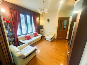 A living room with a sofa, a chair, a small table with a vase, and a door. - EL BOSQUE (Gotemba)
