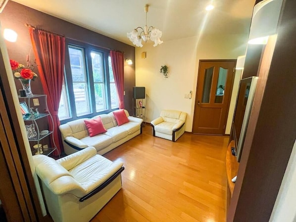 A living room with a sofa, a chair, a small table with a vase, and a door.