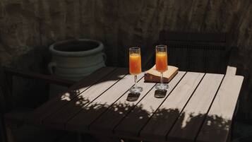 Two glasses of orange juice on a wooden table with a rustic brick wall in the background.
