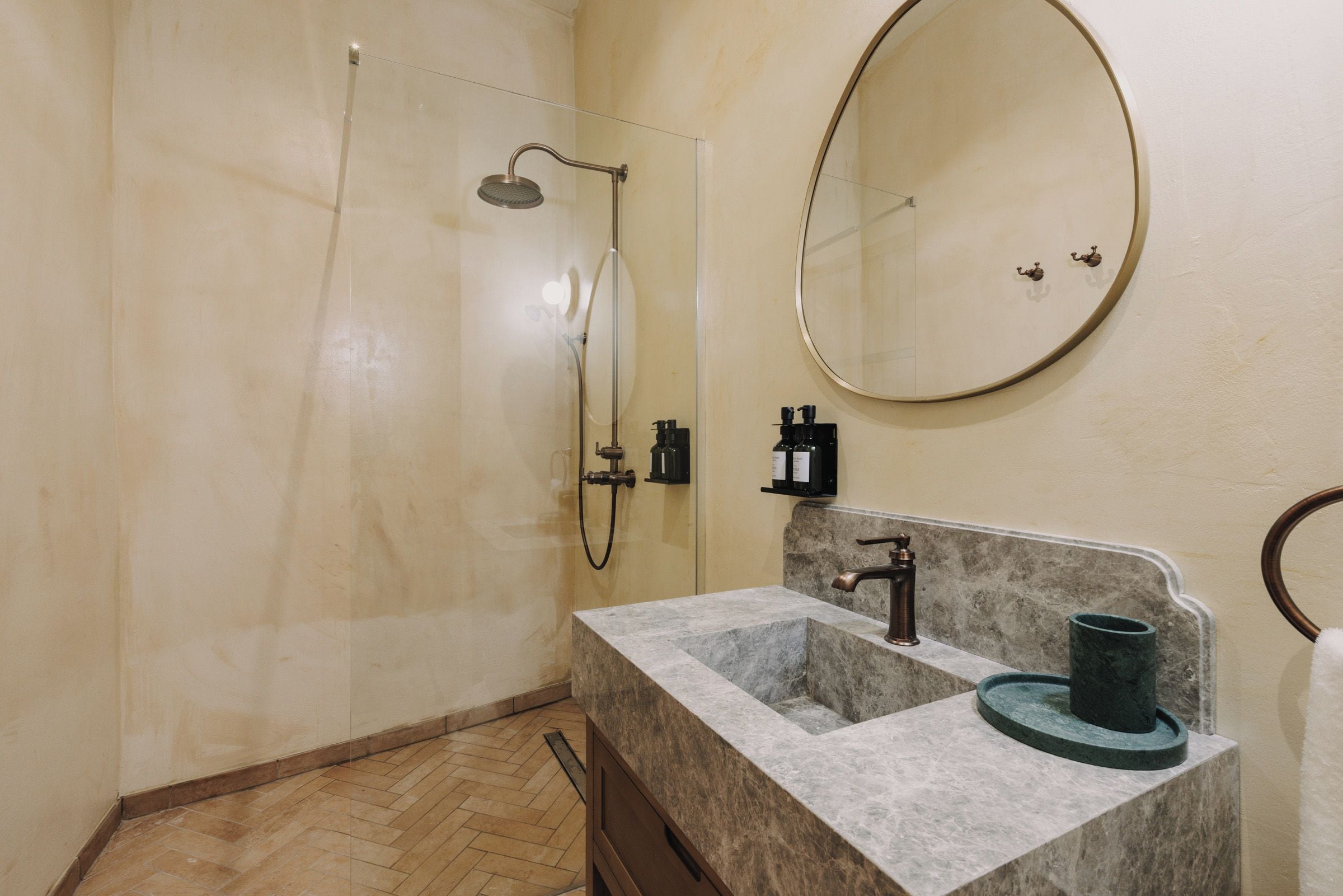 Ein Badezimmer mit Dusche, Waschbecken mit Marmorplatte, Spiegel und Handtuchhalter.