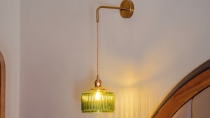 Luminaria de pared con acabado en latón y pantalla de vidrio verde.
