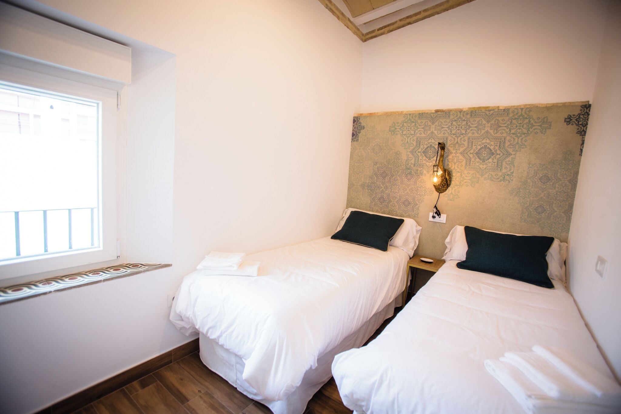 Une chambre d’hôtel avec deux lits, une fenêtre et un mur décoratif.