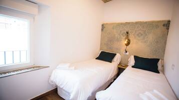 Habitación de hotel con dos camas, una ventana y un detalle decorativo en la pared.