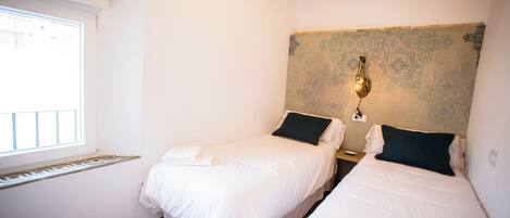 A hotel room with two beds, a window, and a decorative wall.