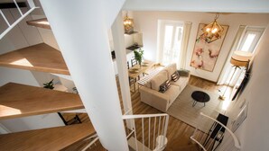 A modern interior with a spiral staircase, a living area with a sofa and coffee table, and a dining area with a table and chairs. - Alijar Casa Boutique (Castilleja de la Cuesta)