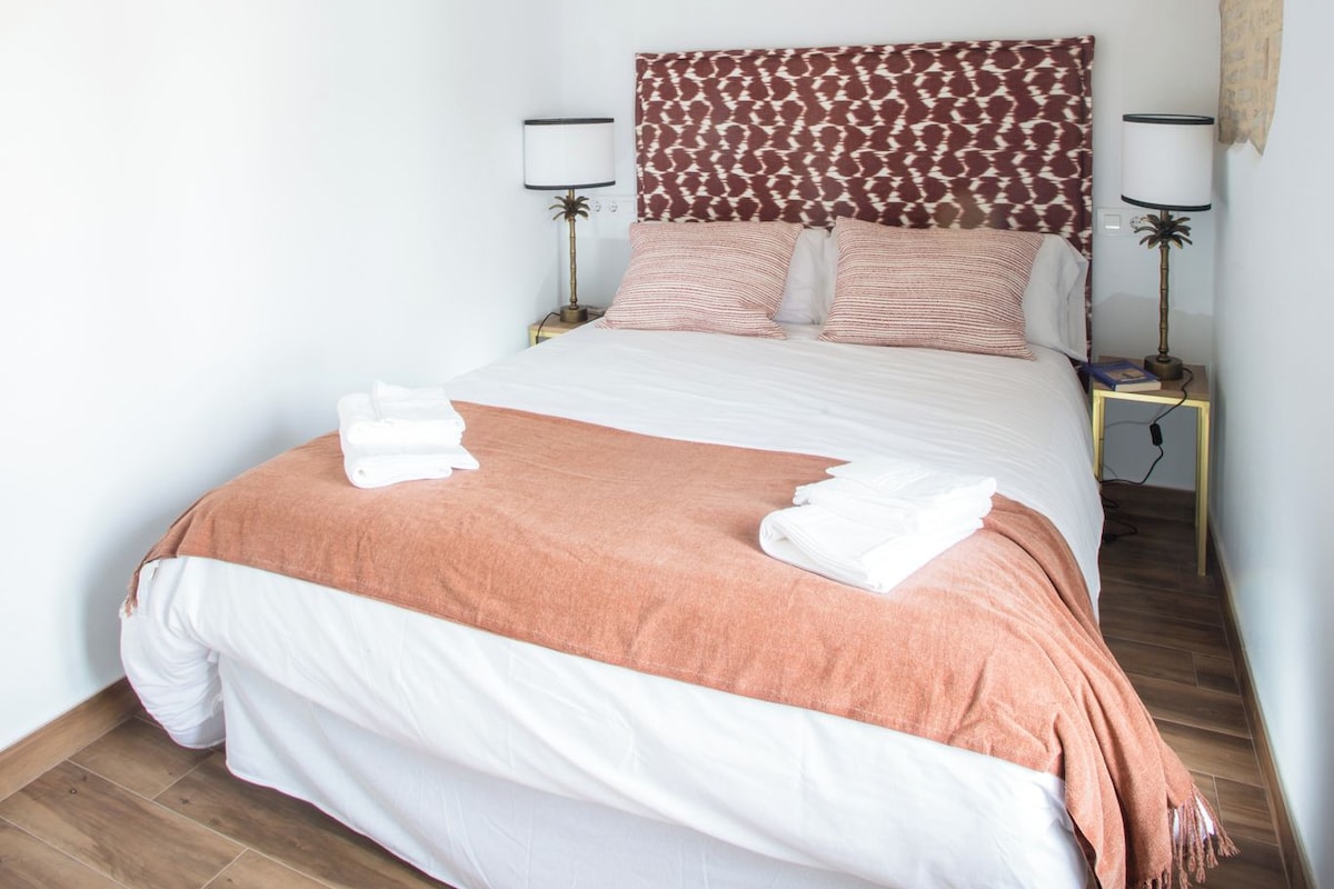 Una camera da letto con un letto, due comodini e una testiera.