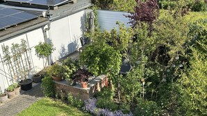 Un jardin résidentiel agrémenté de panneaux solaires, de plantes en pot et d’un chemin en briques.