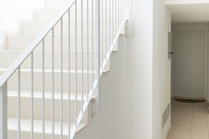Un escalier avec des rampes blanches menant à une porte.