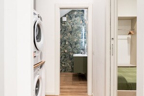 Een wasruimte met een wasmachine, droger en een klein plankje.