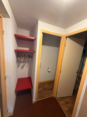 Habitació d'angle amb una prestatgeria vermella, una porta i un sòl de fusta.