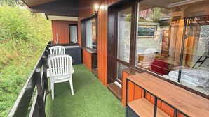 A balcony with artificial grass, white chairs, and a wooden bench.