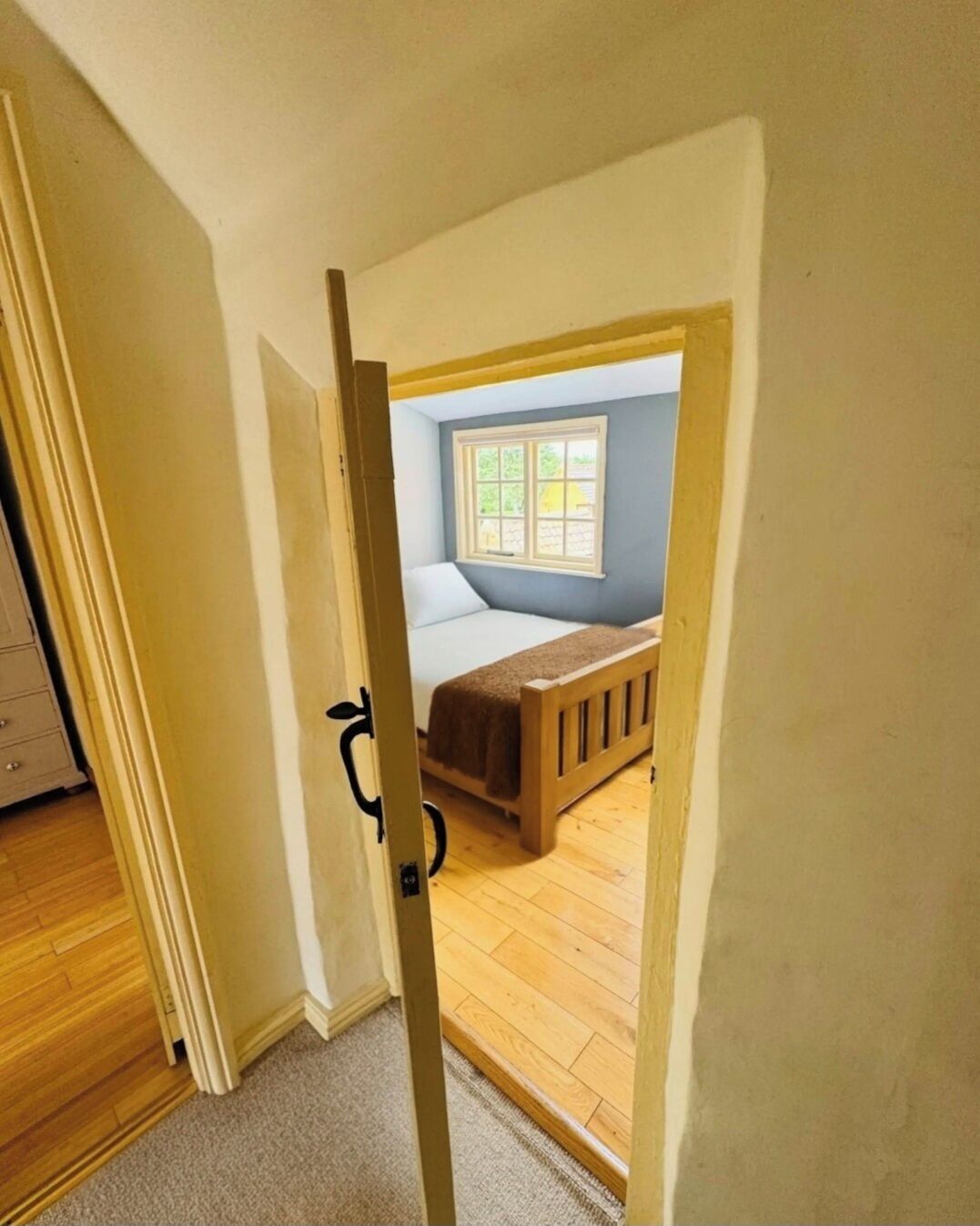 Una camera da letto con un letto, una finestra e una porta che conduce a un'altra stanza.