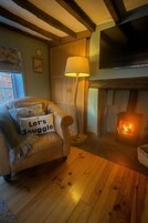 A cozy living room with a fireplace, a sofa with a cushion, a lamp, and a television mounted on the wall.