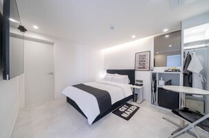 Egy modern szállodai szoba, amelyben található egy ágy, egy éjjeliszemélyzet és egy kis íróasztal széssel.