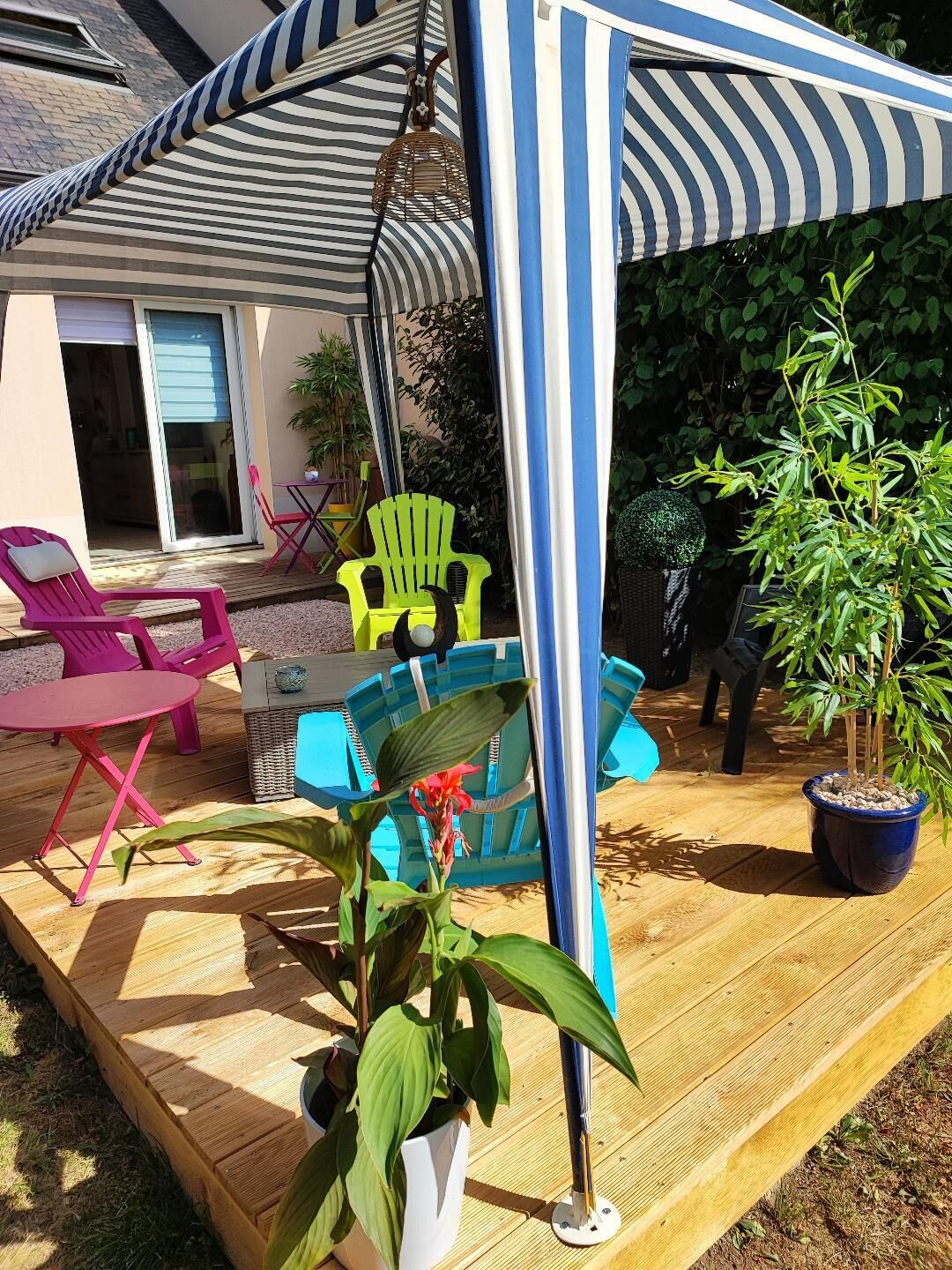 A covered patio area with outdoor furniture, including chairs and a table, and potted plants.