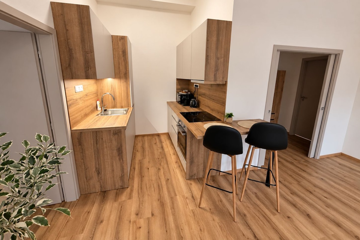 A modern kitchen with wooden cabinetry, a built-in stove, and two black bar stools.