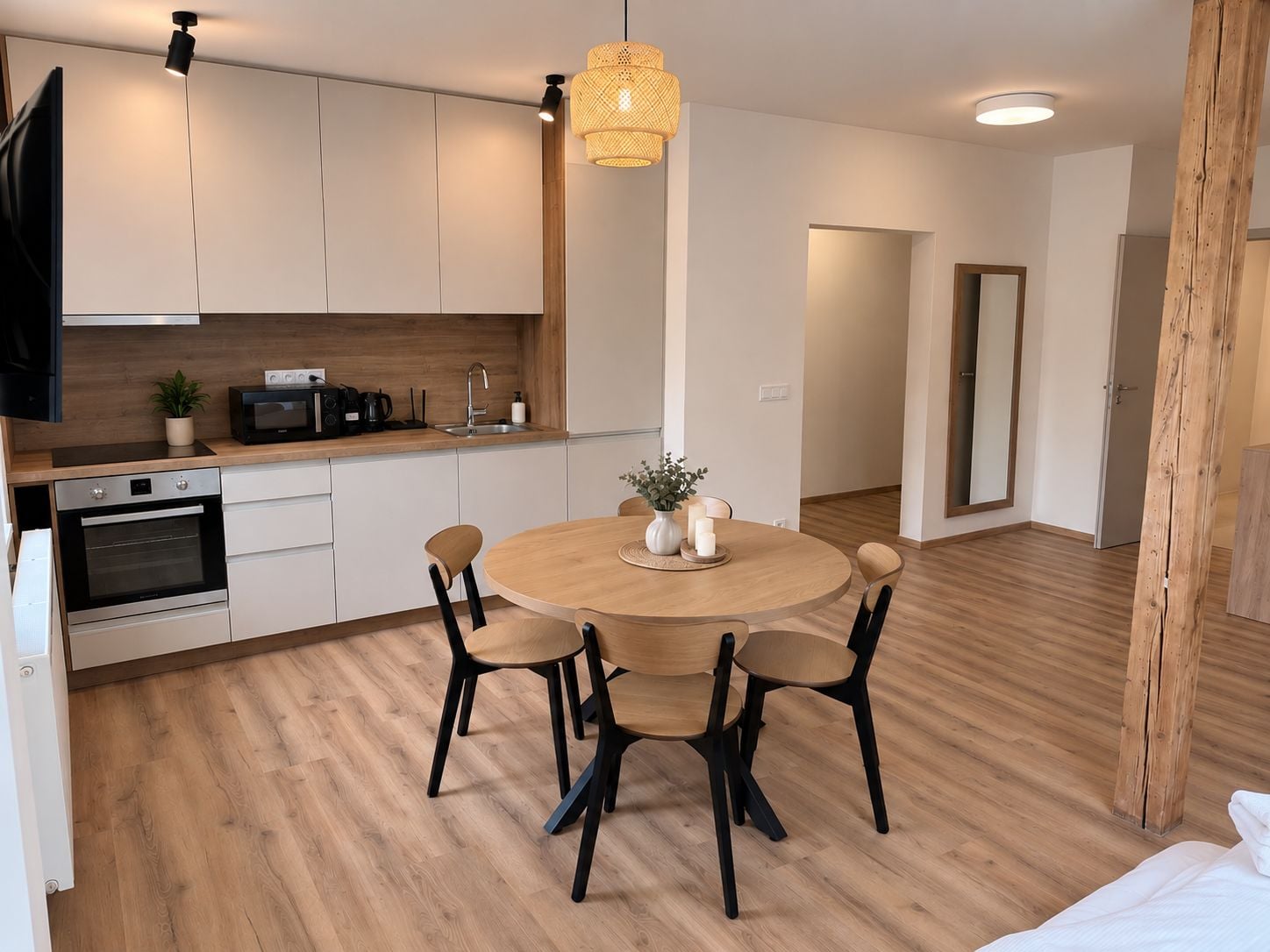 A modern kitchen with white cabinets, a wooden countertop, and a round dining table with four chairs.
