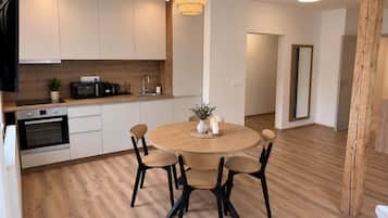 A modern kitchen with white cabinets, a wooden countertop, and a round dining table with four chairs.
