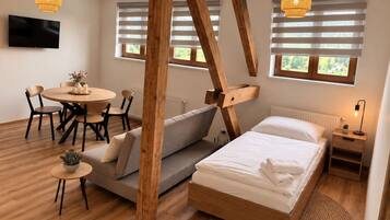 Una camera da letto moderna con un letto in legno, una poltrona, un tavolo da pranzo con sedie e un televisore montato a parete.