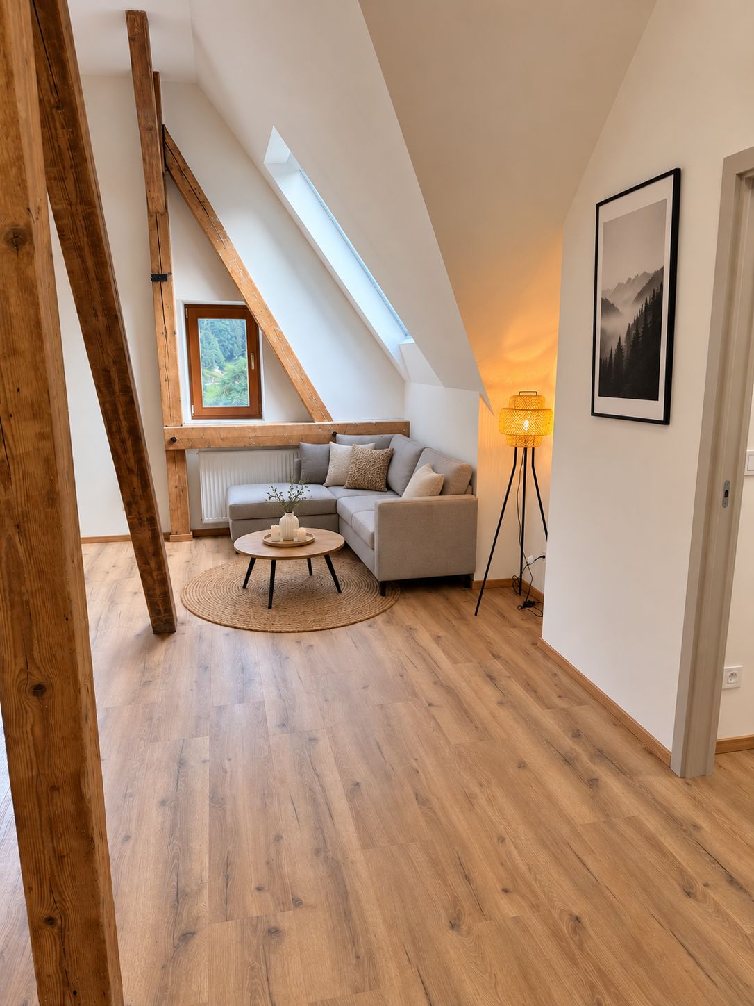Quarto tipo loft moderno com teto inclinado, um sofá aconchegante, uma pequena mesa redonda e um abajur.