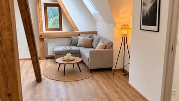 Quarto tipo loft moderno com teto inclinado, um sofá aconchegante, uma pequena mesa redonda e um abajur.