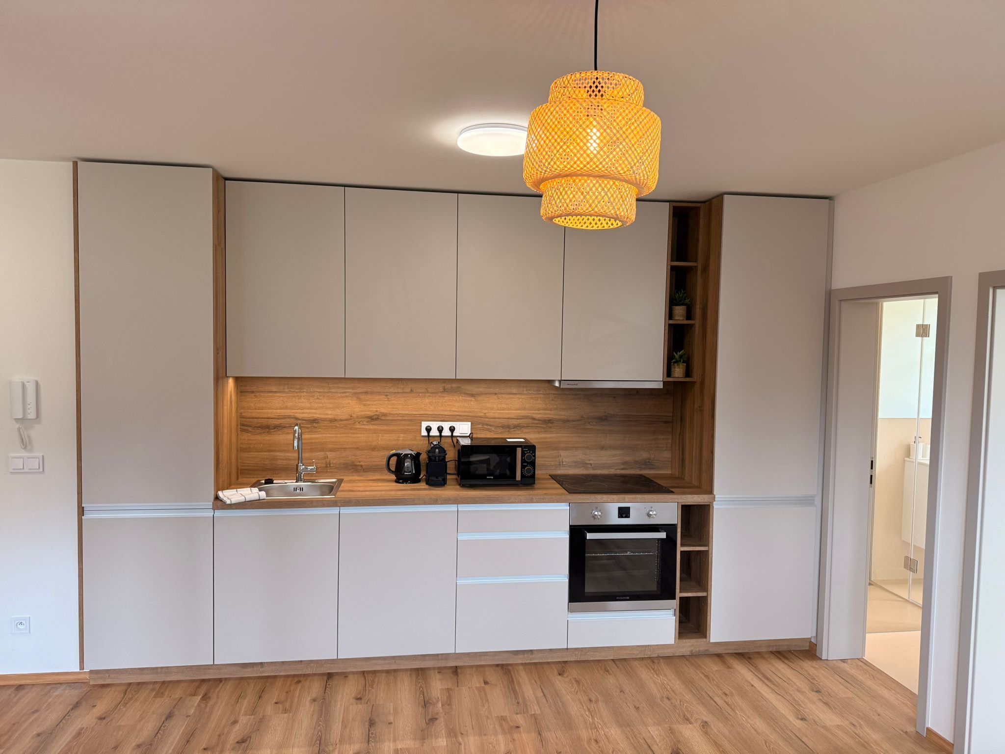 Une cuisine moderne avec un plan de travail en bois, des appareils électroménagers intégrés et un luminaire suspendu.