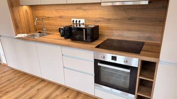 Moderni keittiö, jossa on puinen työtaso, kahvinkeitin, leivänpaahdin ja sisäänrakennettu uuni.