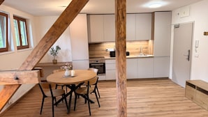 Eine moderne Küche mit weißen Schränken, einem Holztisch mit Stühlen und einer Holzbalkendecke.
