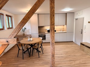 Una cocina moderna con armarios blancos, una mesa de comedor de madera con sillas y una estructura de techo de madera.