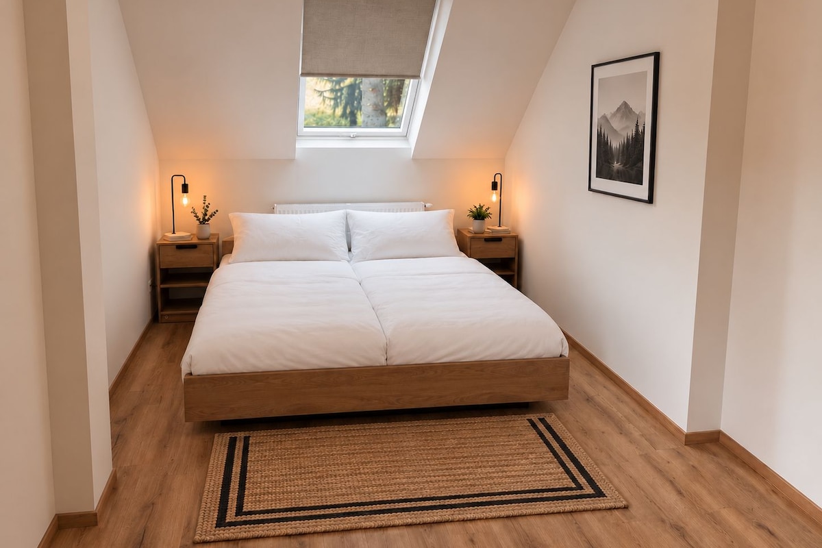 Un dormitorio con cama, mesitas de noche, ventana con vistas, un cuadro en la pared y una alfombra tejida.