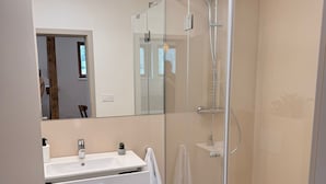 Ein modernes Badezimmer mit Duschkabine aus Glas, einem weißen Waschbecken und einem Spiegel.
