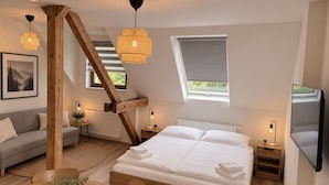 Ein Schlafzimmer mit einem großen Bett, einer Couch, einem Esstisch mit Kerzen und einem an der Wand montierten Fernseher.