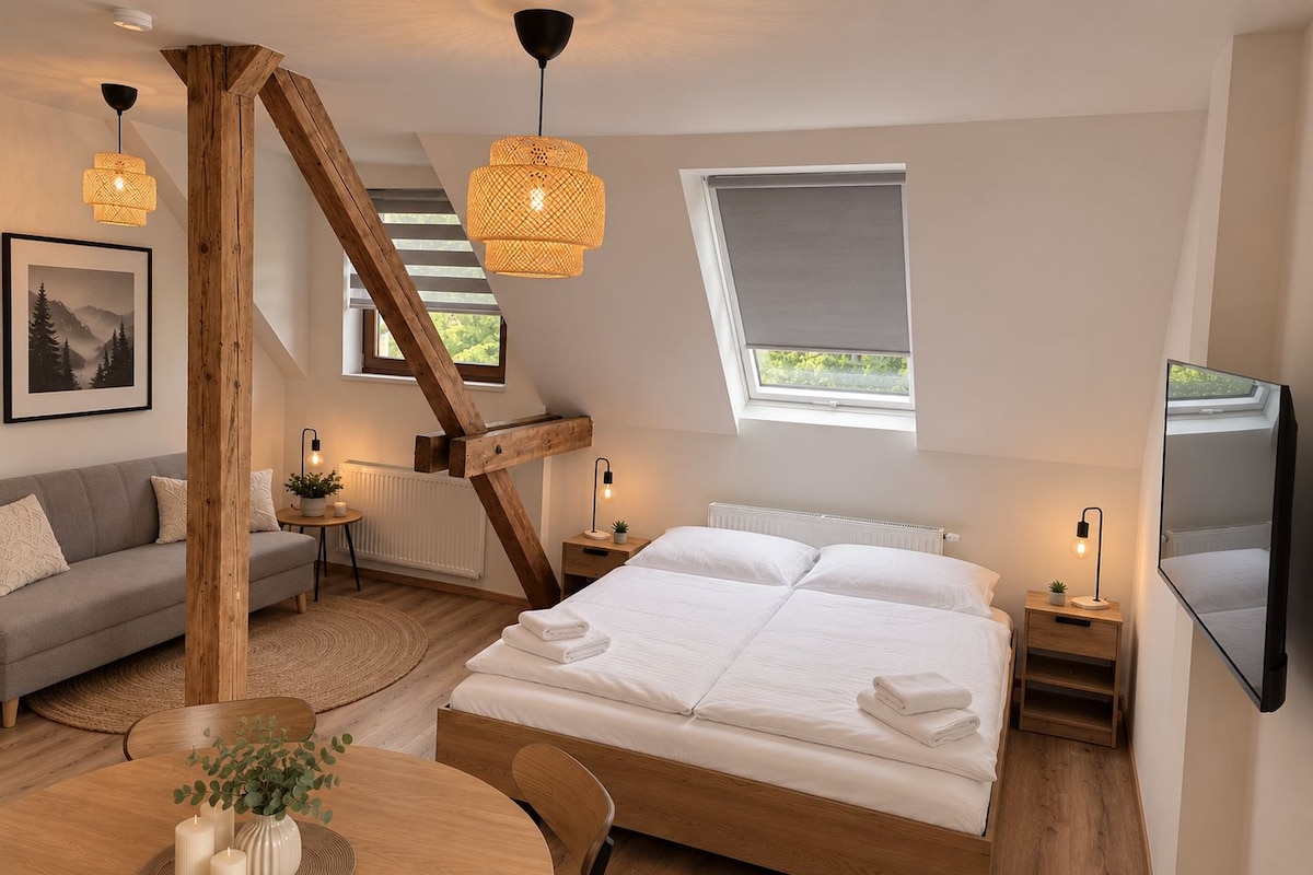 Un dormitorio con una cama grande, un sofá, una mesa de comedor con velas y un televisor montado en la pared.
