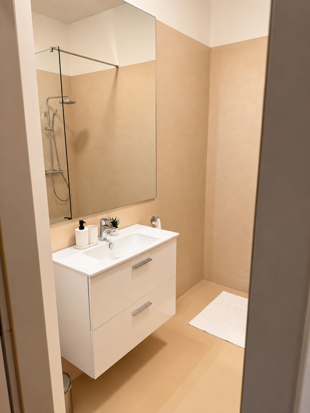 A modern bathroom with a white vanity, a large mirror, and a shower area.