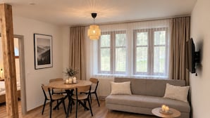 Ein gemütliches Wohnzimmer mit einem runden Holztisch, einem grauen Sofa und einem gewebten Teppich.