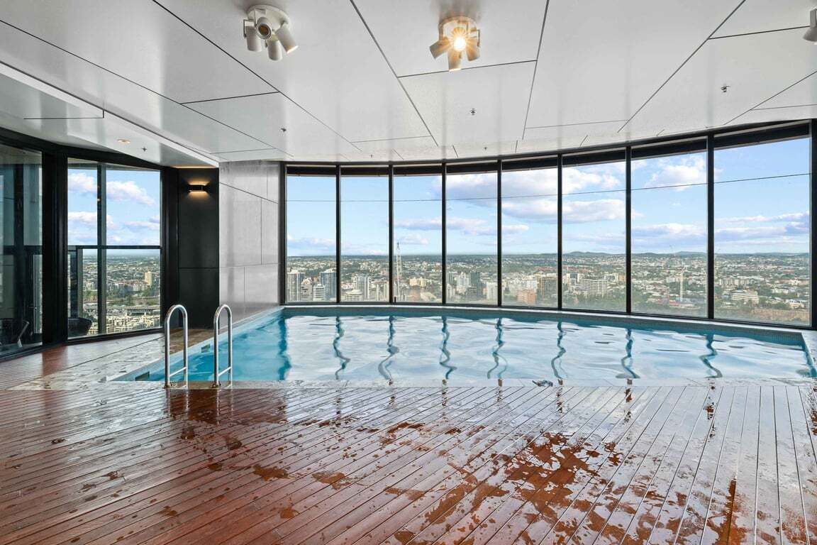 An indoor swimming pool with a view of a cityscape through large windows.