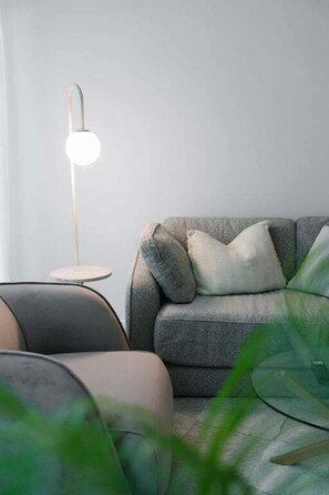 A modern living room with a grey sofa, a floor lamp, and a side table. - NEW! City Centre One-Bedroom Apartment; Sleeps 4 (Brisbane)