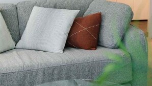 A modern living room with a grey sofa, a glass coffee table, and a remote control on it. - NEW! City Centre One-Bedroom Apartment; Sleeps 4 (Brisbane)