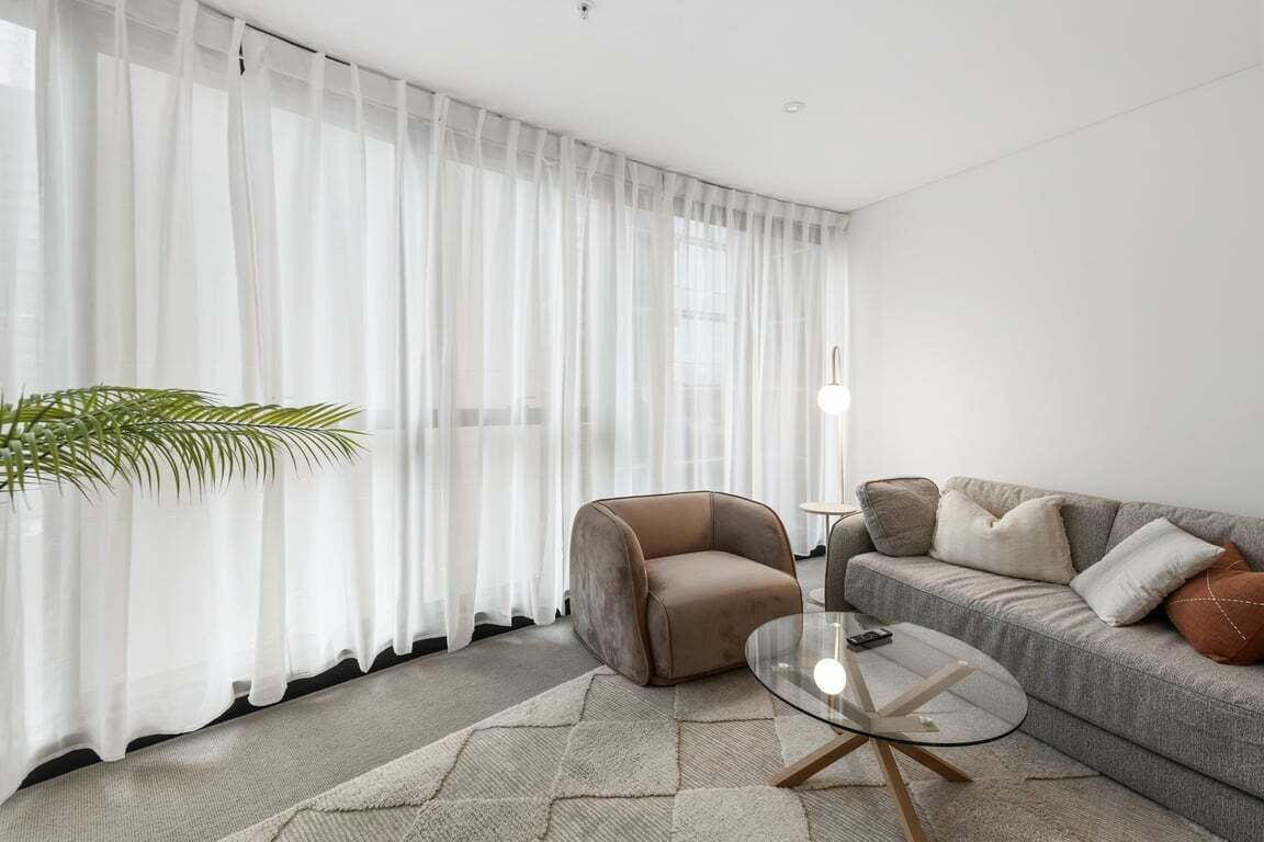 A modern living room with a sofa, armchair, and a glass coffee table.