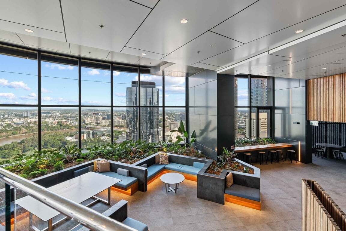 A modern interior with a panoramic city view, a seating area with a round table, and a bar area.