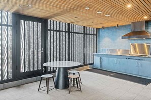 Une cuisine moderne avec une table ronde et des tabourets, un pare-feu bleu et un plafond en bois.