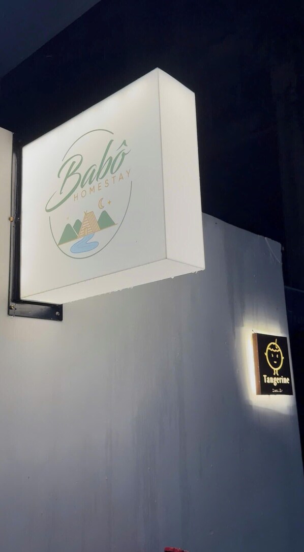 Segnale per 'Babo Home Stay', con logo e una piccola immagine stilizzata di una tenda e montagne.