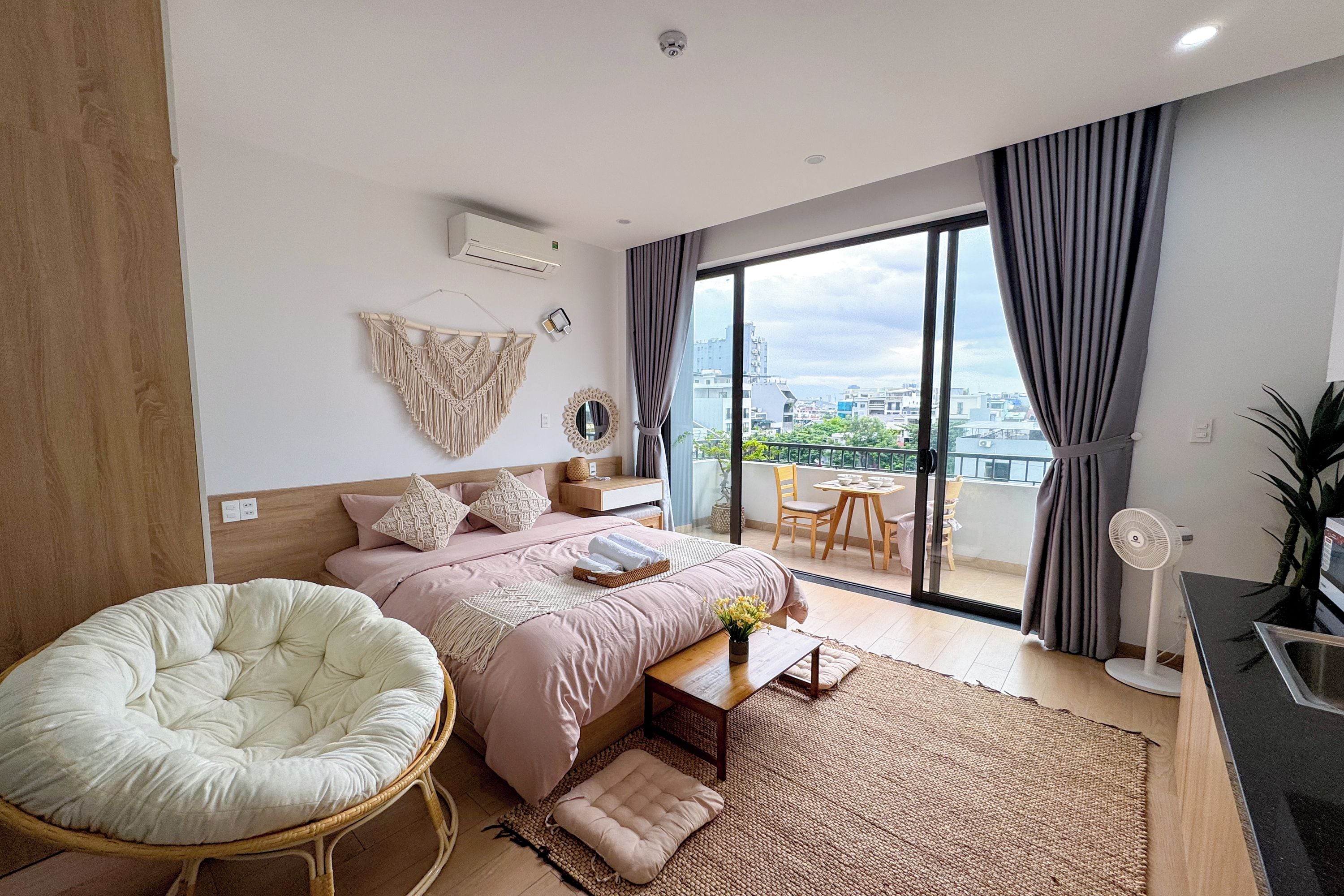 Et moderne soveværelse med seng, stol, lille bord og en balkon med udsigt.